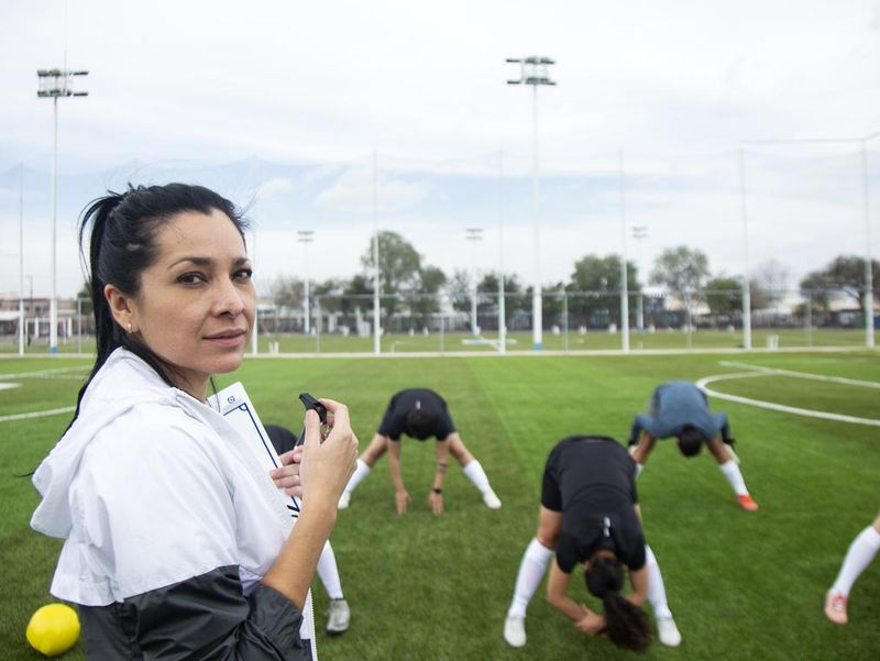 Woman coaching soccer with players warming up