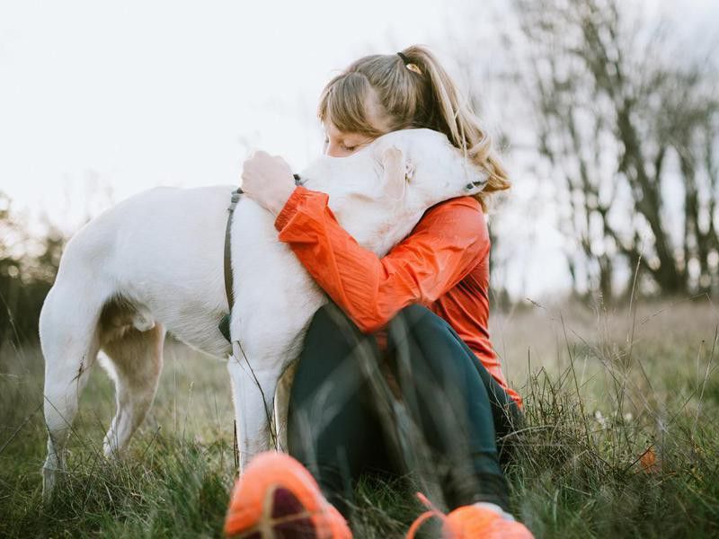 Woman embracing pet dog outdoors