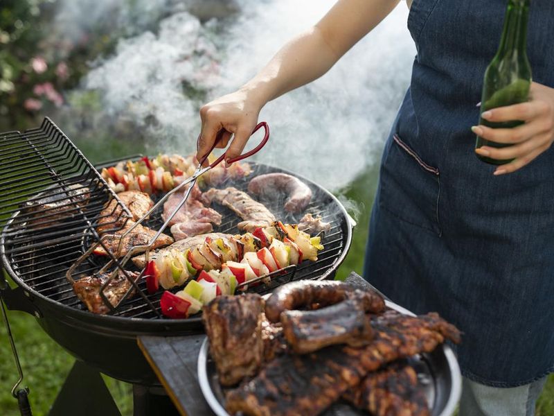 Woman grilling meat and vegetables on the barbeque.