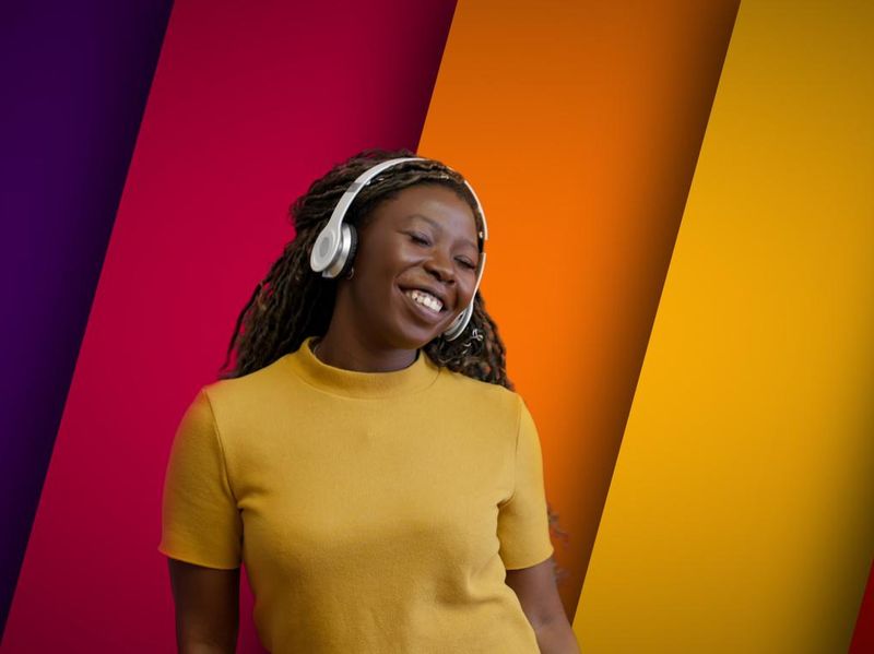Woman in headphones dancing on multi-colored background