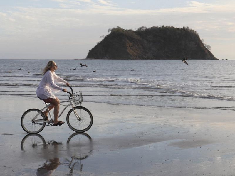 Woman rides bicycle down tropical beach in Costa Rica