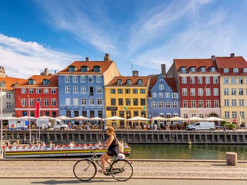 Woman riding bike at Nyhavn Port in Copenhagen, Denmark