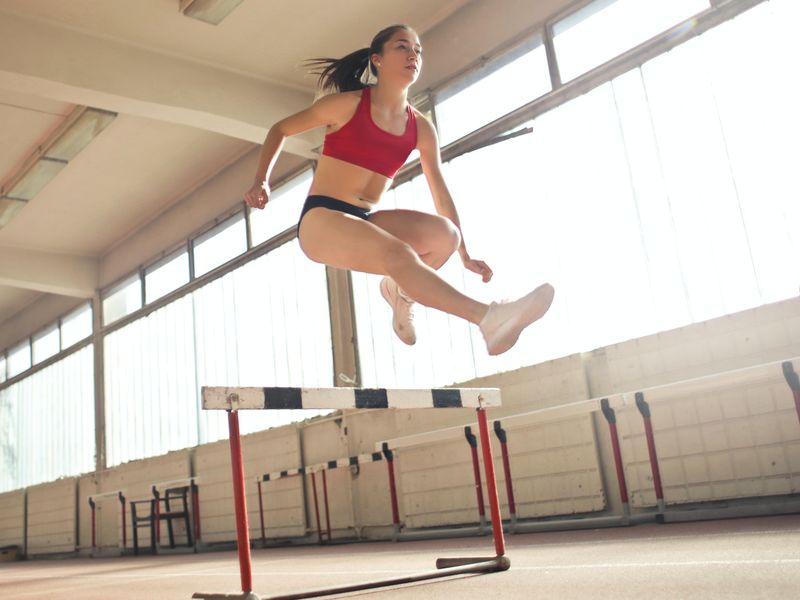 Woman runner jumping over hurdle