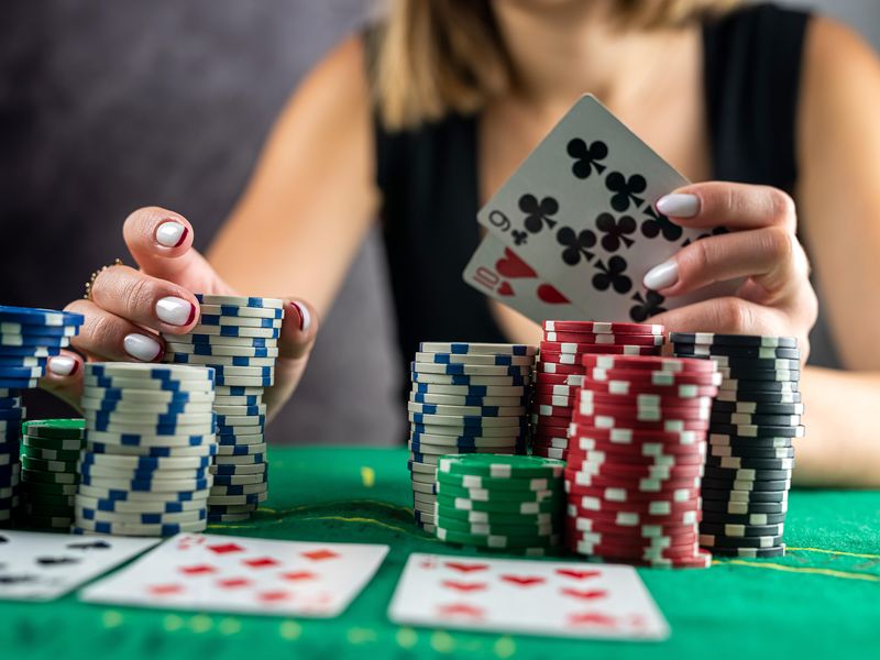 Woman taking poker chips from pile at round poker table