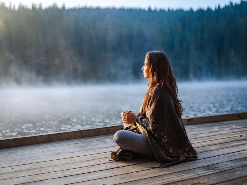 Woman watching sunrise with coffee