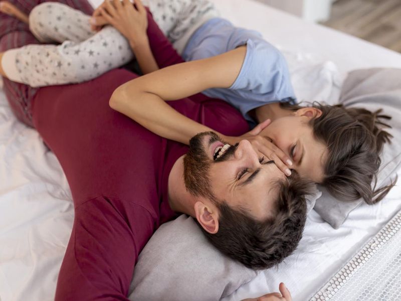 Woman whispering a secret in her man's ear in bed