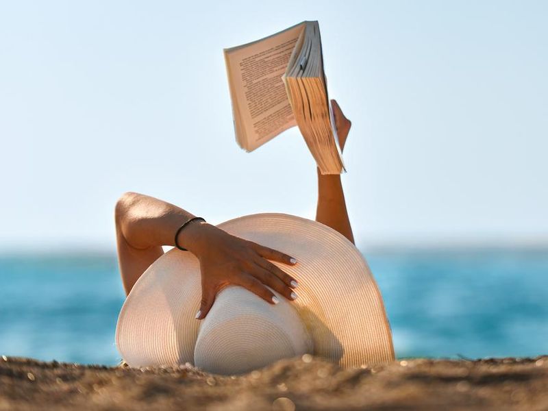 Women reading thriller romance book at the beach
