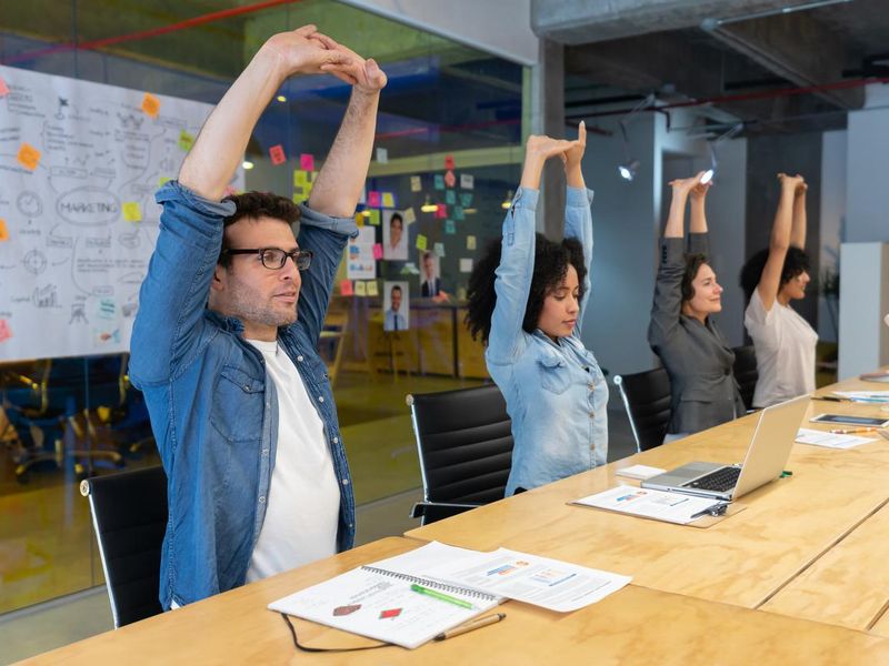 Workers doing stretching exercises in a business meeting