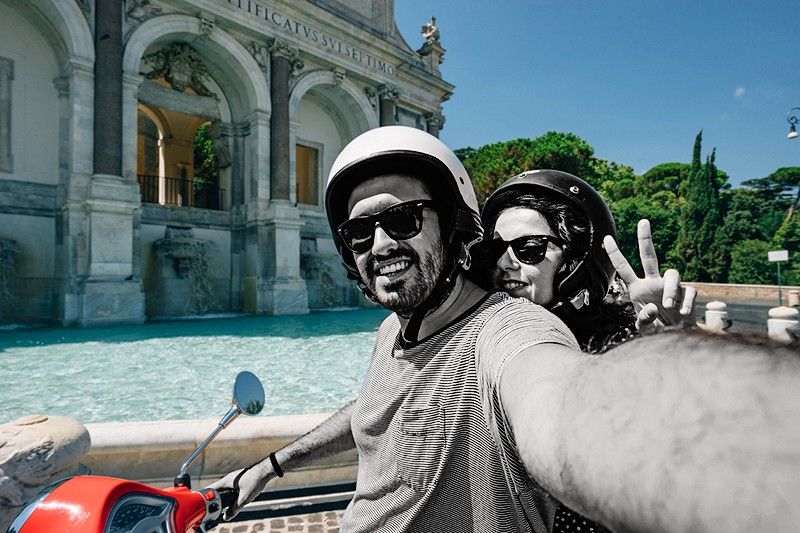 Young adult couple is taking a selfie on a scooter