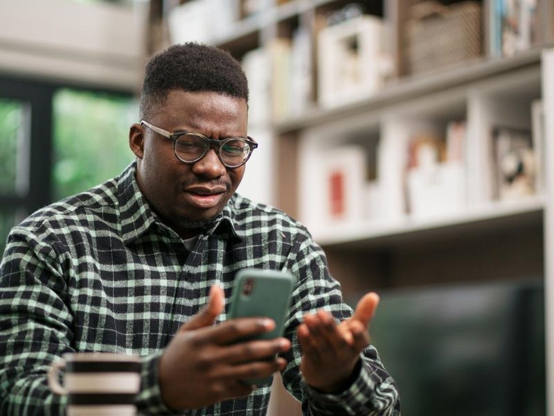 Young African American man having reading bad news on his smart phone