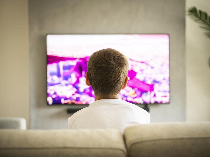 Young boy sitting on sofa and watching TV