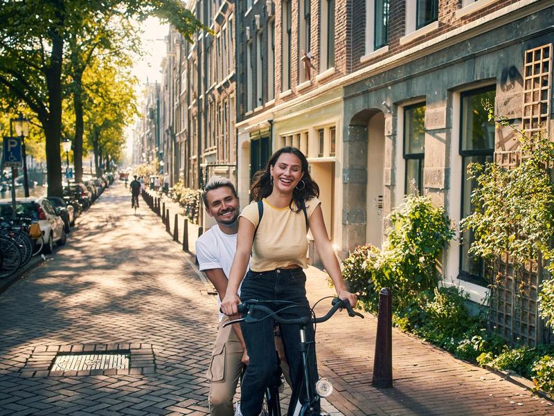 Young couple exploring the city of Amsterdam by bike