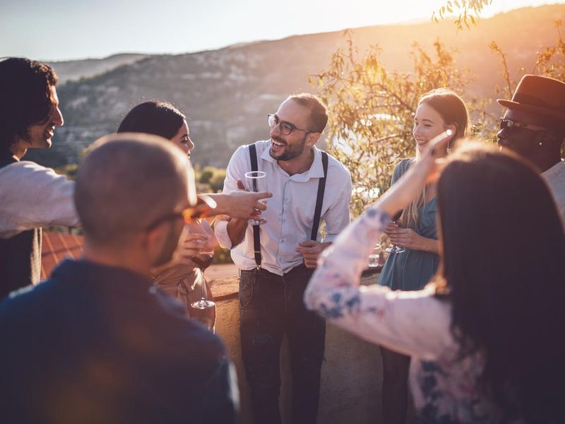 Young elegant multi-ethnic friends drinking wine at countryside cottage party