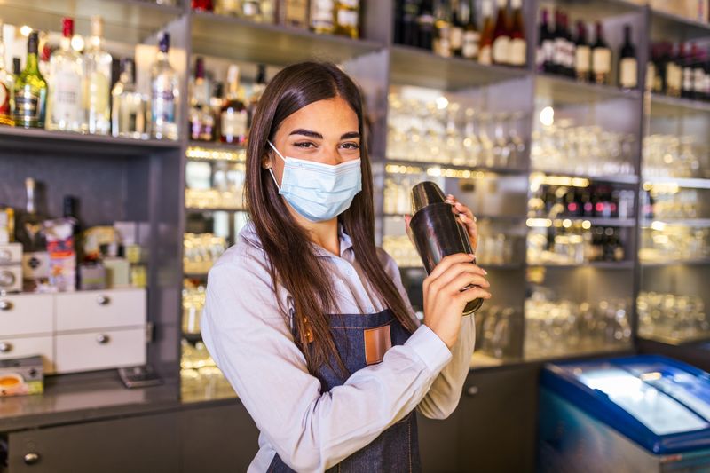Young female bartender making drinks