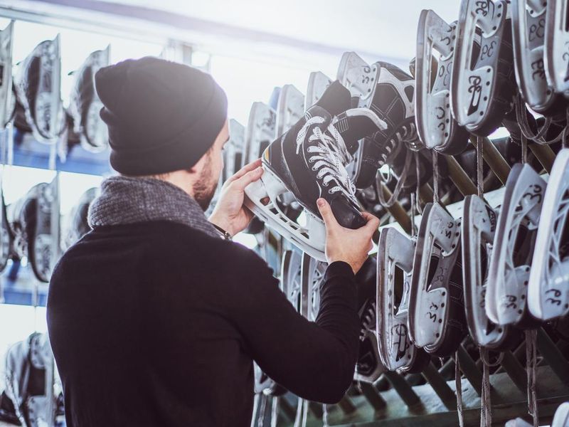 Young guy choosing a pair of skates in a skate hire inside.