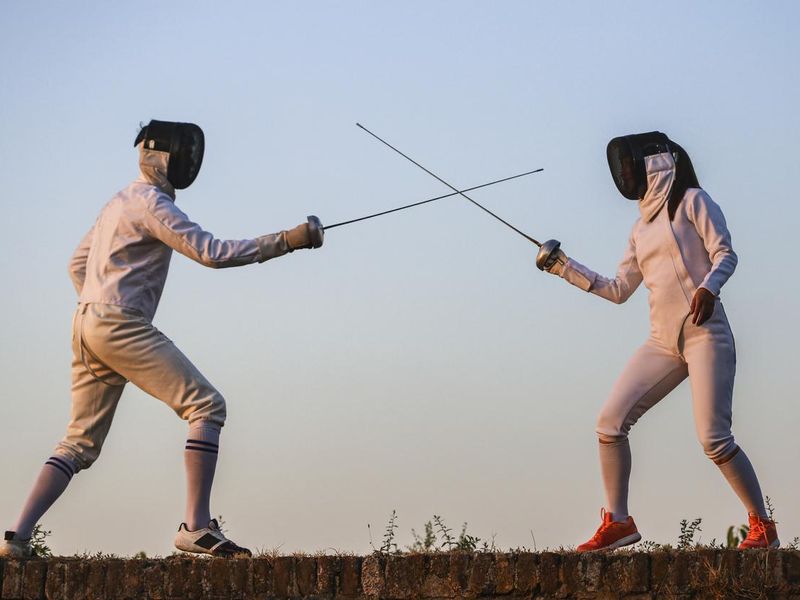 Young man and woman fencing