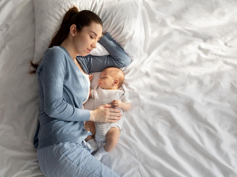 Young mother co-sleeping with newborn baby