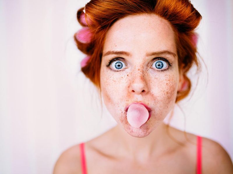 Young redhead woman blows bubble