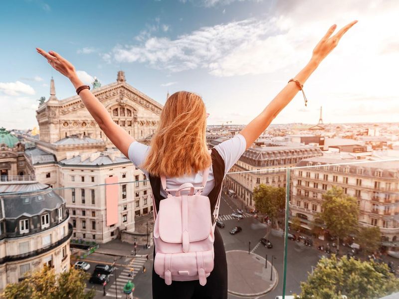 Young student with backpack standing on a rooftop enjoying France