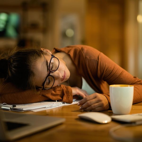 Exhausted woman taking a nap on a desk while working late at night at home.