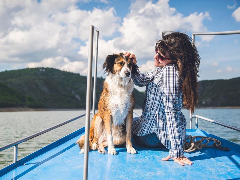 Young woman enjoys a boat ride on river with her dog