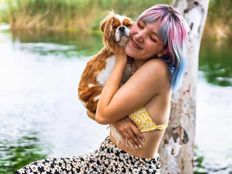 Young woman hugs her dog by a lake