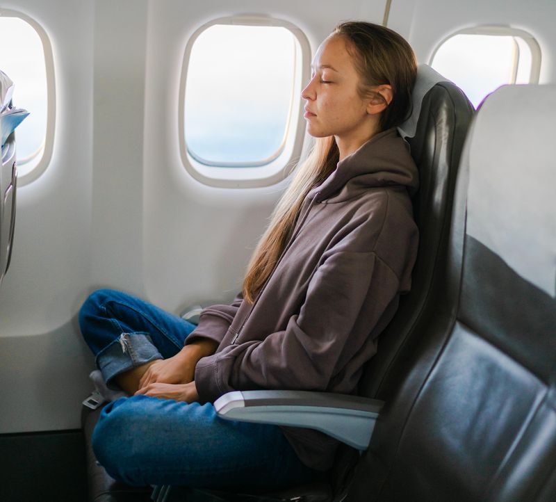 Young woman meditating on airplane