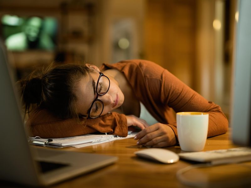 Young woman sleeping at desk while working at home